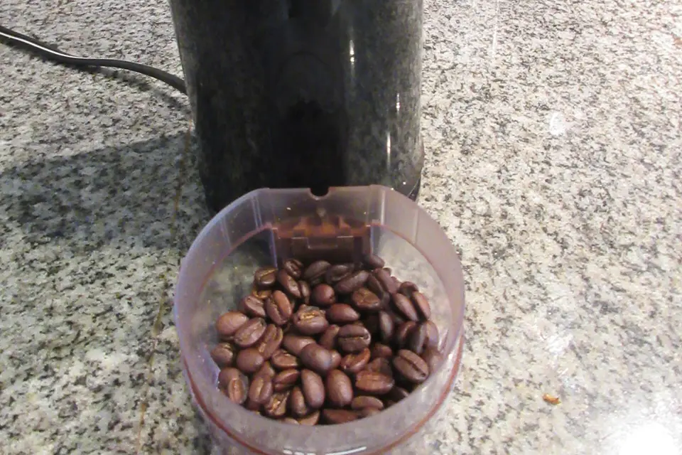Coffee beans beside an electric grinder